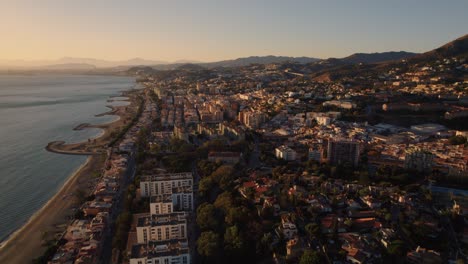 Aerial-forward-moving-drone-shot-over-El-Candado-beach-in-Malaga-Spain-with-beautiful-sunlight-on-seashore-and-beach-houses