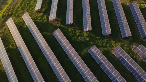 Top-down-scenic-aerial-of-photovoltaic-solar-panels-at-sunset,-sideways