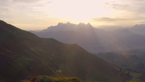 Goldener-Sonnenaufgang-Sonnenstrahlen-über-österreich-Tirol-Kitzbüheler-Alpen-Und-Silhouettiertes-Kitzbühler-Horn