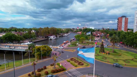Argentinian-Flag-Waving-on-Roundabout-of-Delta-del-Parana,-Tigre,-Aerial-Shot-from-Drone-During-Daylight,-Street-Car-Traffic