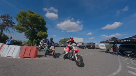 FPV-drone-circles-group-of-motorcycle-riders-leaving-pit-and-joining-racetrack-circuit
