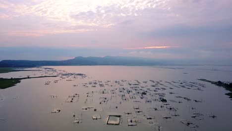 Epic-dolly-in-view-of-several-fish-cages-floating-on-lake-in-Southeast-Asia-at-sunrise
