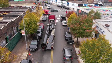 Brooklyn-NYC-USA,-Truck-and-Long-Trailer-With-Steel-Structures-Moving-in-Reverse-on-Street,-Drone-Shot