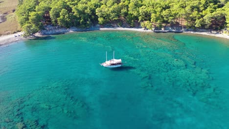 Aerial-View,-Sailing-Boat-Anchored-in-Shallow-Turquoise-Mediterranean-Sea-Water