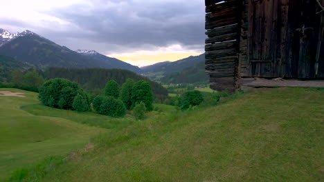 Aerial-view-passing-rustic-wooden-hut-overlooking-lush-High-Tauern-national-park,-Salzburg-state