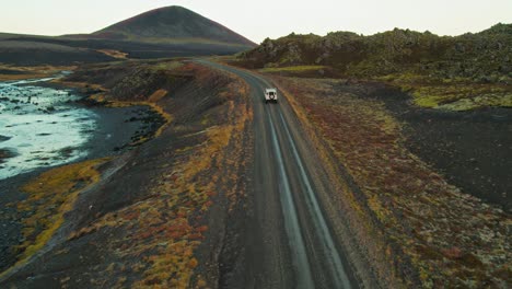 Land-Rover-Blanco-Conduciendo-Por-Una-Carretera-Solitaria-En-Un-Colorido-Paisaje-Volcánico-Durante-Un-Viaje-De-Aventura-Por-Carretera