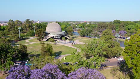 Planetarium,-Buenos-Aires-City,-Aerial-Above-Forests-of-Palermo,-Jacaranda-Trees-and-Lilac-Violet-Flowers-during-the-Day