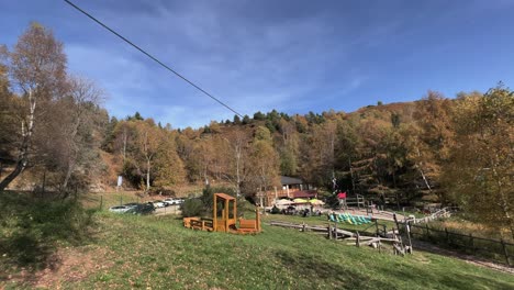 Courageous-kids-have-fun-with-zip-line-at-rope-adventure-park,-forest-in-background-and-sky-for-copy-space