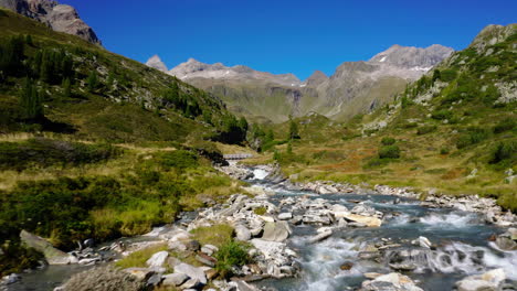 Aerial-view-following-stream-flowing-through-Zillertal-Alps-in-the-Tyrol-valleys-mountain-range