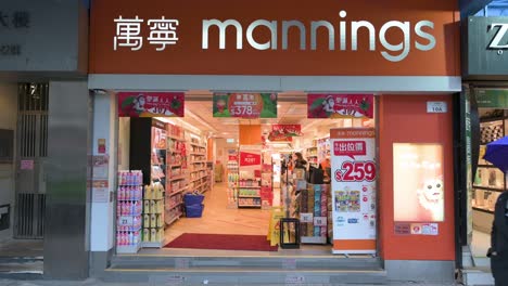 Fußgänger-Gehen-An-Einer-Apotheke-Vorbei,-Die-Während-Der-Grippesaison-In-Hongkong-Körperpflege,-Hygieneprodukte-Und-Medikamente-Anbietet-Und-Verkauft