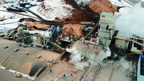 Aerial-view-of-buildings-at-a-sawmill-in-the-winter:-shot-of-waste-material-handling-in-action
