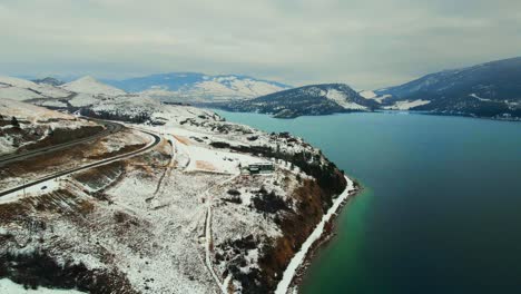 Winterwunderland:-Türkisfarbener-Waldsee-In-Kelowna-Mit-Schneebedeckten-Roten-Felsen-Und-Okanagan-highway-97-Am-Ufer-Entlang