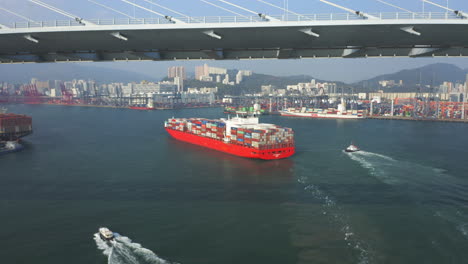 Riesiges-Rotes-Containerschiff,-Das-Sich-Dem-Liegeplatz-Im-Containerhafen-In-Hongkong-Nähert,-Nachdem-Es-Die-Steinmetzbrücke-Passiert-Hat
