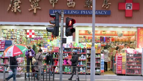 Chinesische-Kunden-Werden-Während-Der-Grippesaison-In-Einer-Apotheke-Gesehen,-Die-Körperpflegeprodukte,-Hygieneprodukte-Und-Medikamente-Kauft,-Während-Fußgänger-In-Hongkong-Daran-Vorbeigehen