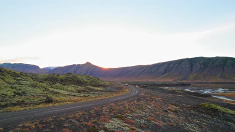 Establishing-Shot-of-Vibrant-Volcanic-Landscape-In-Iceland-With-White-SUV-Driving-On-Countryside-Road