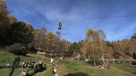 Kids-enjoy-flying-hanging-on-zip-line-at-rope-adventure-park,-forest-in-background-and-sky-for-copy-space