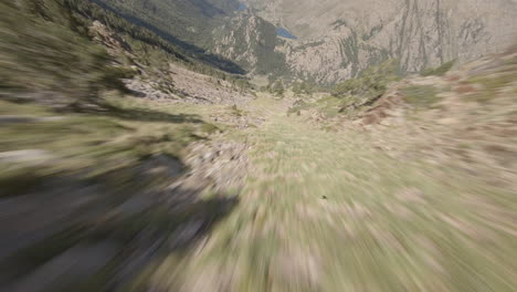 Extreme-FPV-sport-drone-flying-fast-down-rocky-mountain-in-Puymorens,-forward