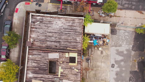 Revealing-Drone-Shot-of-hole-in-Rooftop-of-Old-Building-to-Streets-of-Brooklyn-Suburbs-With-Crane-and-Truck-on-Construction-Site