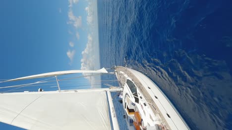 Vertikale-Aufnahme-Einer-Yacht,-Die-Im-Sommer-Mit-Ruhigem-Blauem-Wasser-Im-Ozean-Kreuzt