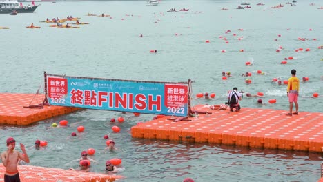 Schwimmende-Teilnehmer-überqueren-Die-Ziellinie,-Wenn-Sie-Am-Jährlichen-Schwimmwettbewerb-New-World-Harbour-Race-In-Hong-Kong-Teilnehmen