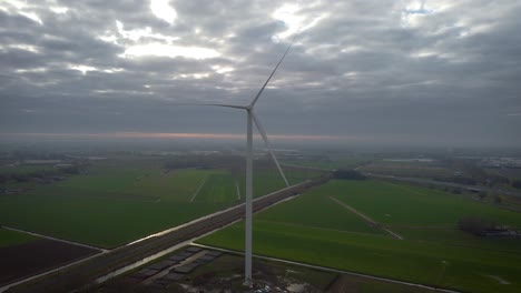 Wind-turbine-with-overcast-weather-in-the-Netherlands,-along-with-train-tracks-in-the-background