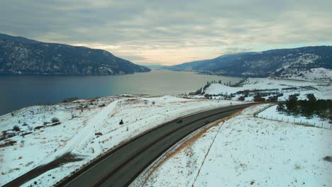 Winter-Magic-in-Central-Okanagan:-An-Airborne-View-of-Snow-Covered-Landscape,-Traffic-on-Highway-97,-and-Wood-Lake