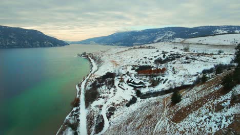 Aerial-Perspective-of-Wood-Lake-in-Kelowna:-A-View-from-Above-of-the-Turquoise-Water-and-Snow-Covered-Red-Cliffs-along-the-Shore
