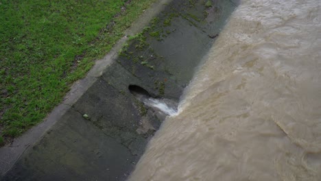 Culverts-drain-murky-city-water-into-overflowing-river-after-heavy-rain