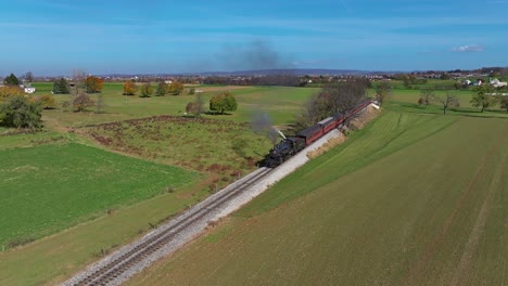 An-Aerial-View-of-a-Steam-Train-Blowing-Smoke-as-it-Travels-Thru-Country-Farmlands-on-a-Sunny-Fall-Day