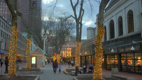 People-Strolling-In-The-Street-With-Trees-Wrapped-In-Christmas-Lights-In-Quincy-Market,-Boston,-Massachusetts