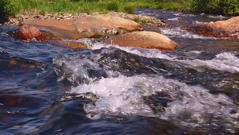 Gimbal-static-shot-of-a-fast-flowing-mountain-stream-in-slo-mo