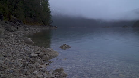 Lago-Tranquilo-Eibsee-Agua-Transparente-Con-Nubes-Bajas-A-Través-De-La-Montaña-Zugspitze-Al-Amanecer