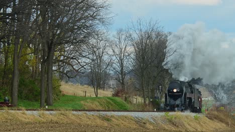 A-View-of-a-Steam-Passenger-Train-Approaching-From-a-Long-Distance-on-a-Cold-Fall-Day-With-Lots-of-Smoke