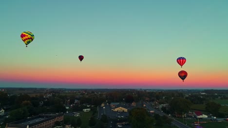An-Aerial-View-of-Multiple-Hot-Air-Balloons-Floating-in-the-Sky-During-a-Festival-With-Crowds-Watching,-on-a-Summer-Day