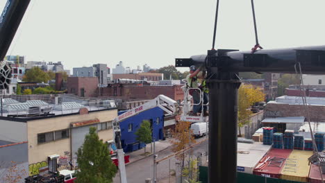 Aerial-View-of-Installers-in-Crane-Basket-Fixing-Catwalk-on-Billboard-Metal-Support,-Drone-Shot