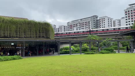 Vista-Panorámica-Del-Tren-Mrt-Que-Pasa-Por-Bukit-Canberra,-Un-Centro-Deportivo-Y-Comunitario-Integrado-Con-El-Nuevo-Centro-Hawker-En-Singapur