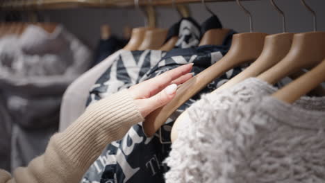 Closeup-of-a-woman's-hand-going-through-clothes-at-a-clothing-store