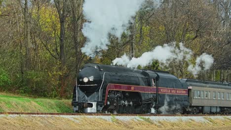 A-View-of-a-Steam-Passenger-Train-Approaching-From-a-Distance-on-a-Cold-Fall-Day-With-Lots-of-Smoke