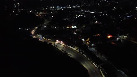 Imagen-Fija-En-ángulo-Alto-Que-Muestra-El-Movimiento-Del-Tráfico-A-Lo-Largo-De-Una-Carretera-De-Pueblo-Mexicano-En-Una-Noche-Oscura