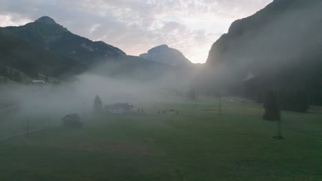 a-sunrise-drone-flight-through-a-valley-slowly-rising-above-the-clouds-to-reveal-the-mountain-range-of-the-dolomites