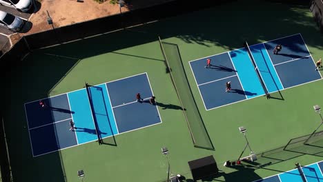 Pickleball-games,-two-courts-doubles-playing-the-sport,-static-aerial-over-matches