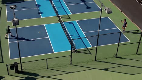 Pickleball-game,-singles-match-on-outside-court,-two-men-playing,-aerial-drove-static-view