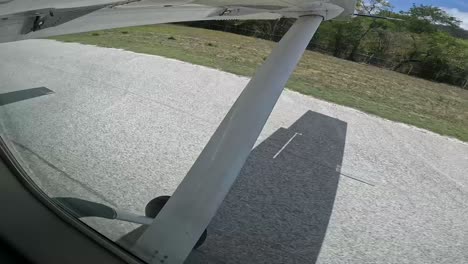 Single-engine-airplane-landing-on-rural-Costa-Rican-runway-at-midday,-Side-window-view