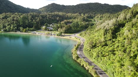 Feriencampingplatz-Am-See,-Blauer-See,-Palmenwaldstraße-Und-Tourist-Auf-Paddelbord-4k-drohnenaufnahme-In-Neuseeland
