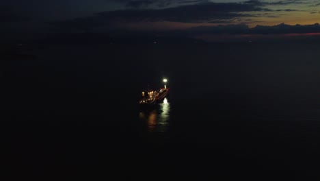 Aerial-approaching-boat,-oil-tanker-parked-in-sea-at-night