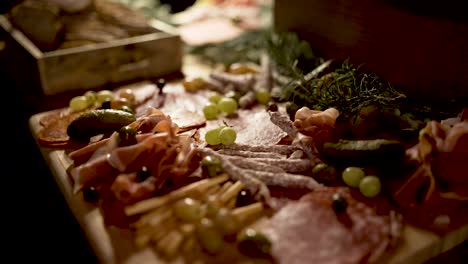Cold-cuts,-grapes-breadsticks-and-prosciutto-appetizer-on-cutting-board-with-rosemary-herbs,-Close-up-dolly-out-shot