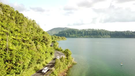 Blue-lake,-palm-forest-road-and-tourist-on-paddle-bord-4k-drone-shot-in-New-Zealand