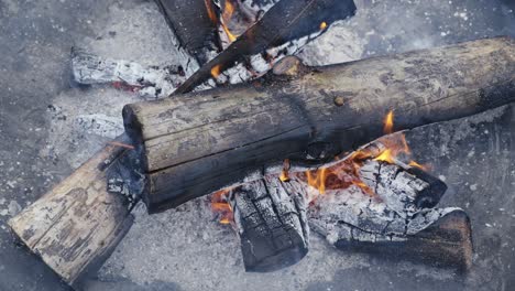 Top-closeup-of-log-wood-burning-fire-and-hot-embers-outside-during-frozen-winter