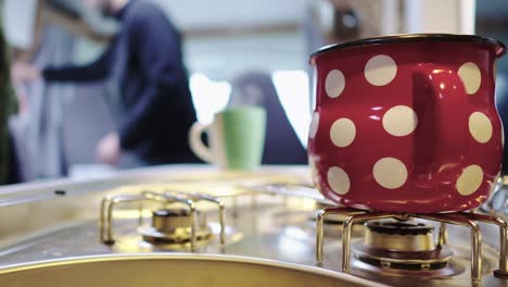 Steaming-mug-on-cooker-or-stove-in-campervan-kitchen,-person-in-blurry-background