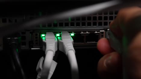 Unplugging-four-networking-ethernet-cables-into-network-server-switch-by-hand,-Close-up-shot